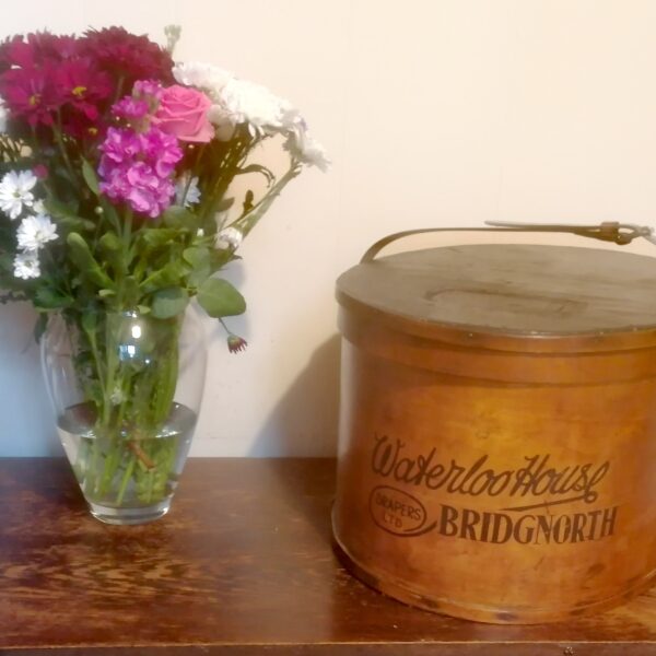 Vintage Hat Box Resting on the table next to a vase of flowers
